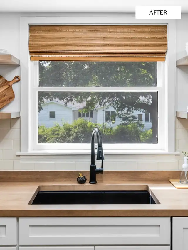 White cabinets with black undermount sink, black faucet and butcher-block counter under a window