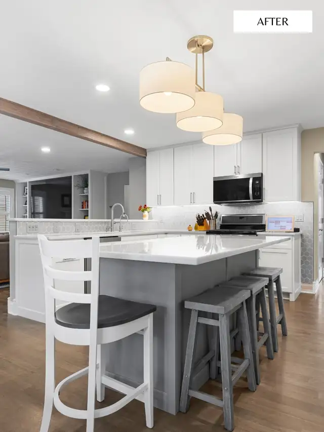 White kitchen with gray island, white counters, drum pendant lights and barstools after a cabinet project