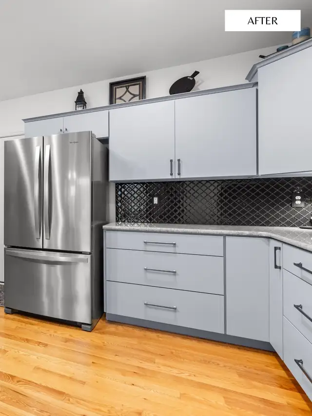 Refaced gray-blue cabinets with black arabesque tile backsplash, stainless refrigerator and oak floor
